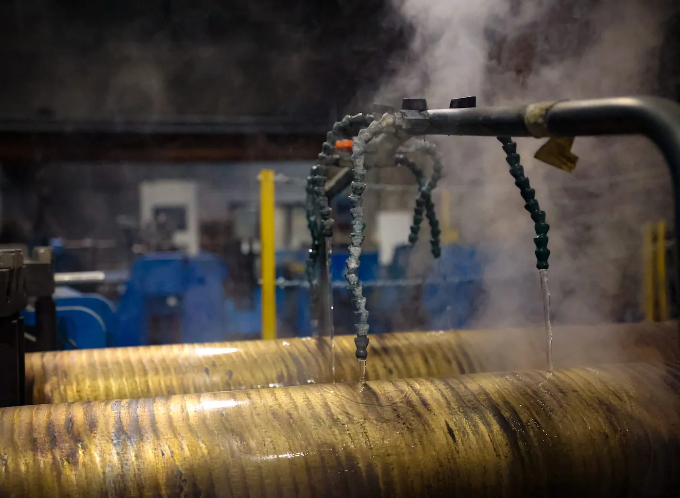 Bronze bars in continuous casting cooled with water, steam and the workshop in the background
